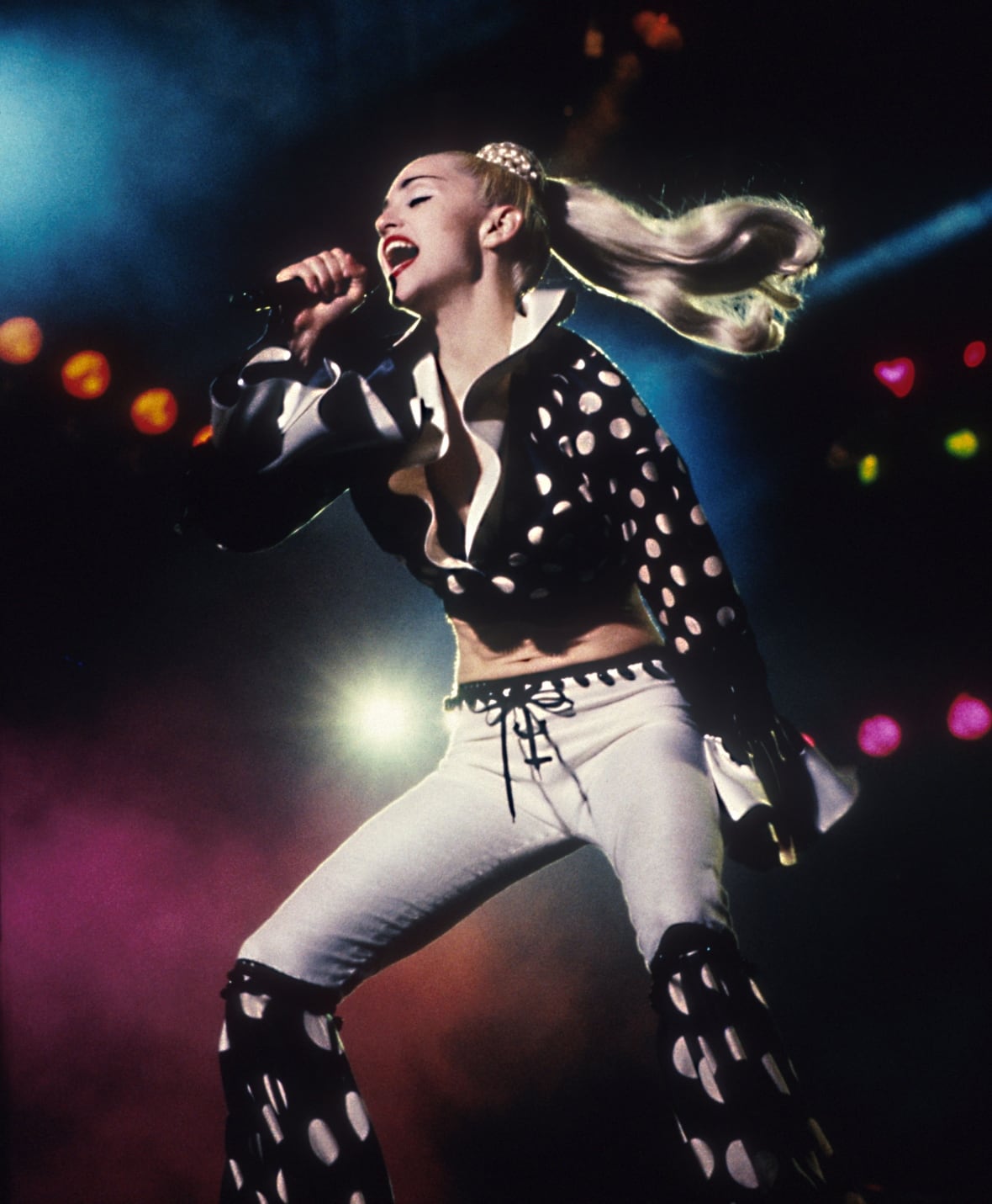 A woman wearing polka dots and singing on stage.