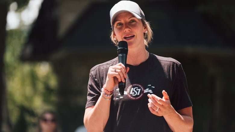 A woman speaks to a crowd with a microphone.