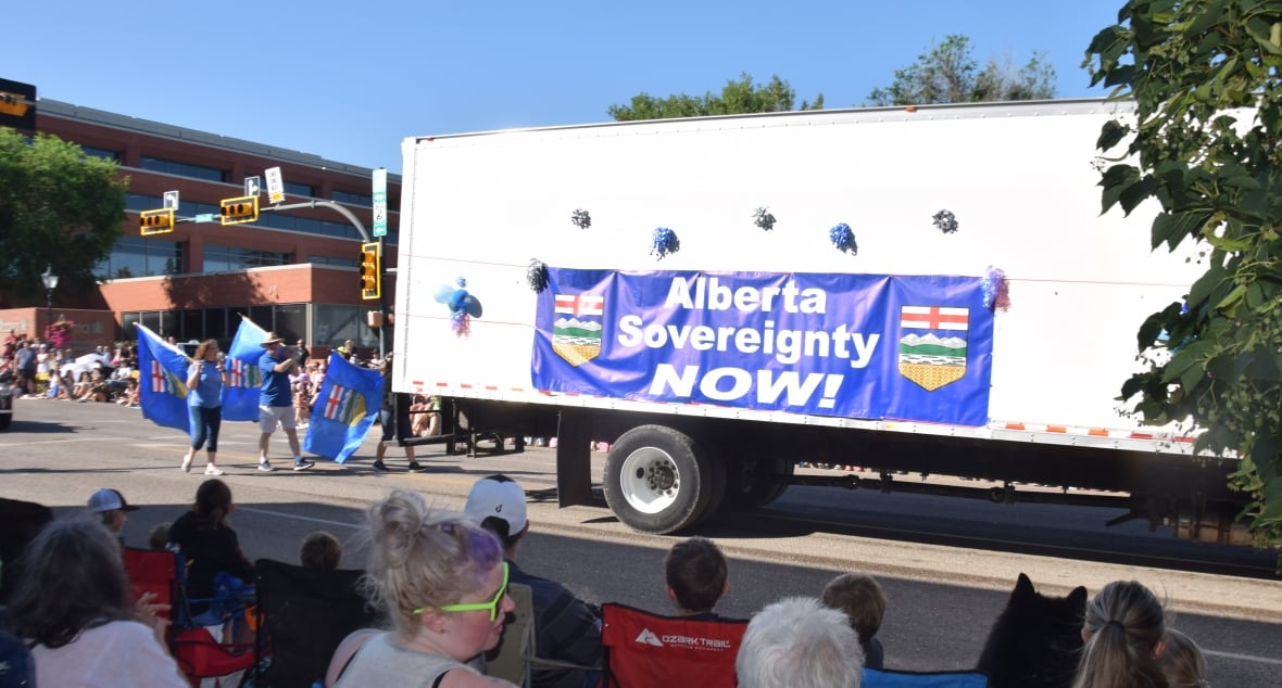 A truck bearing a sign reading Alberta Sovereignty Now! takes part in a parade.