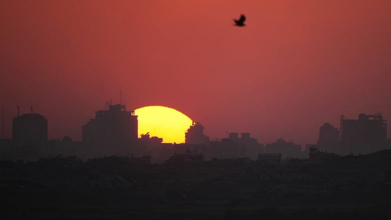 The sun is seen setting over damaged building in the Gaza Strip in July 2025.