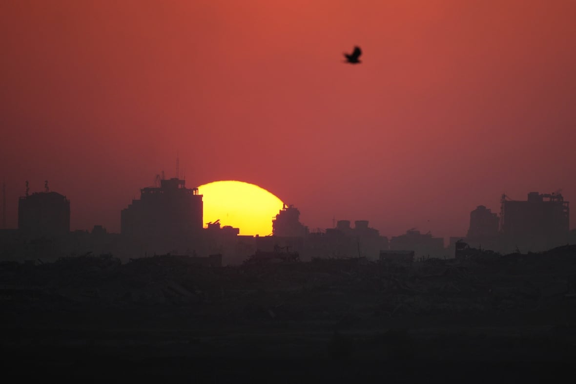 The sun is seen setting over damaged building in the Gaza Strip in July 2025.