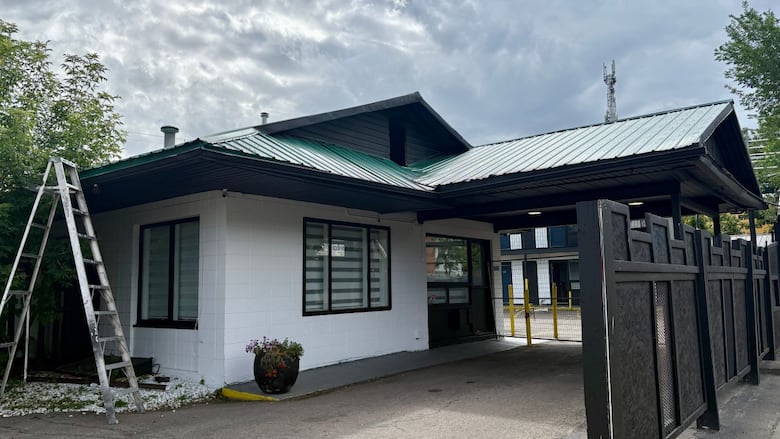 White washed building with green tin roof, looks retro