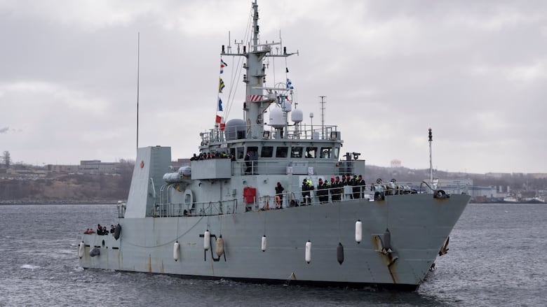 A blue-grey ship moves through the water.