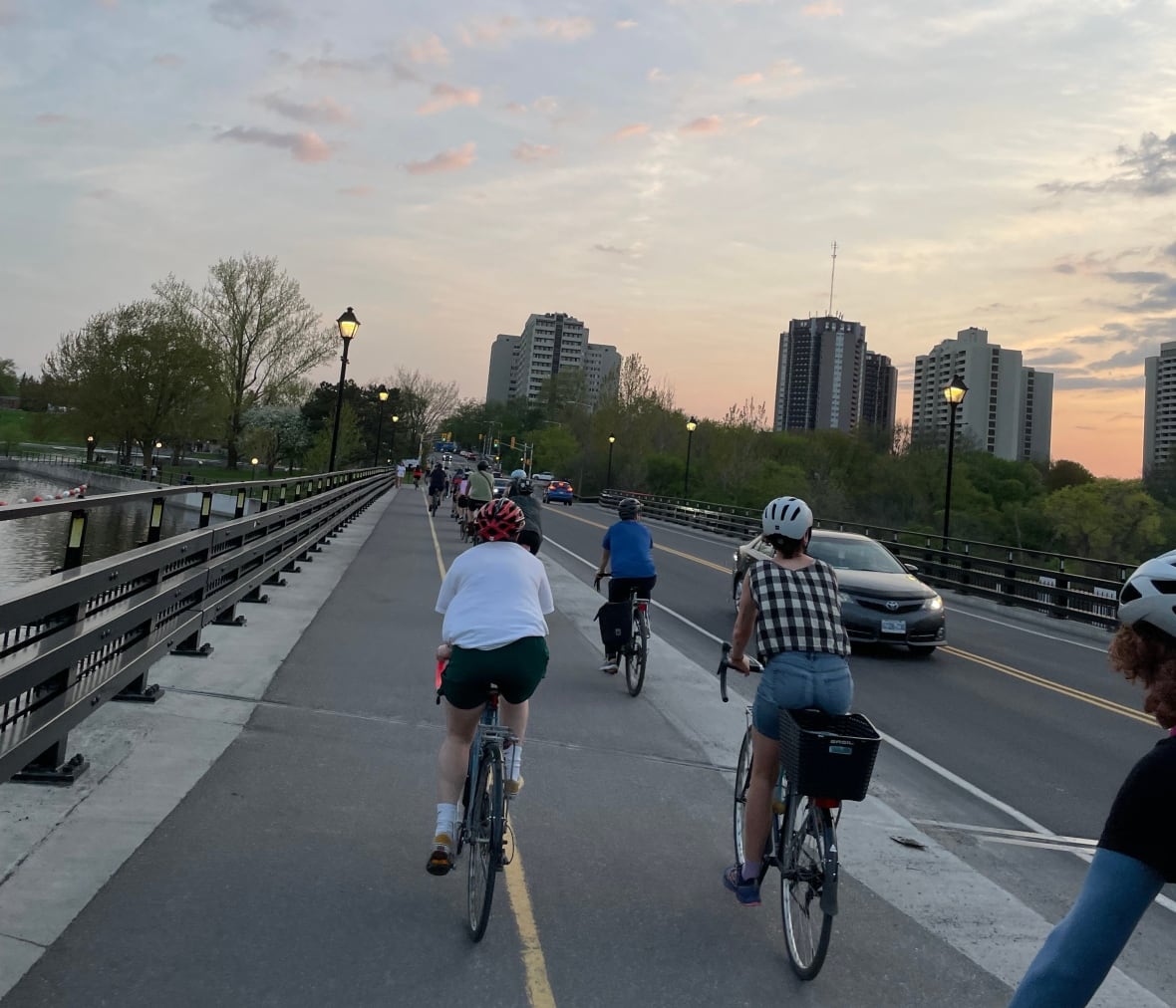 A group of people bike together on a rode at dusk.