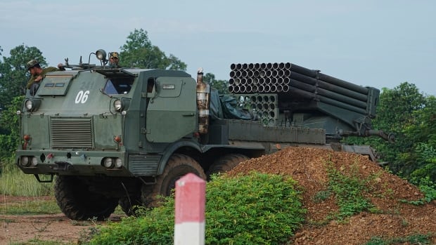 A military tank is shown travelling a rural area.