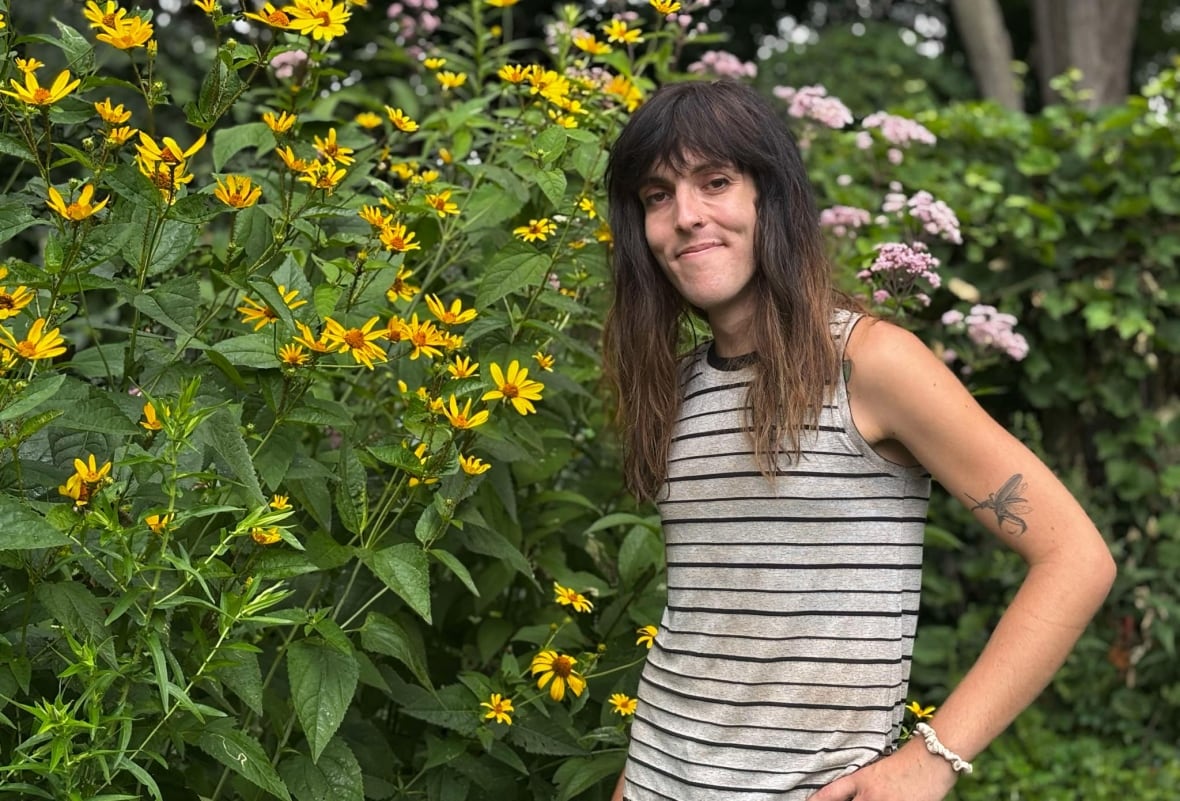 A person stands next to tall plants