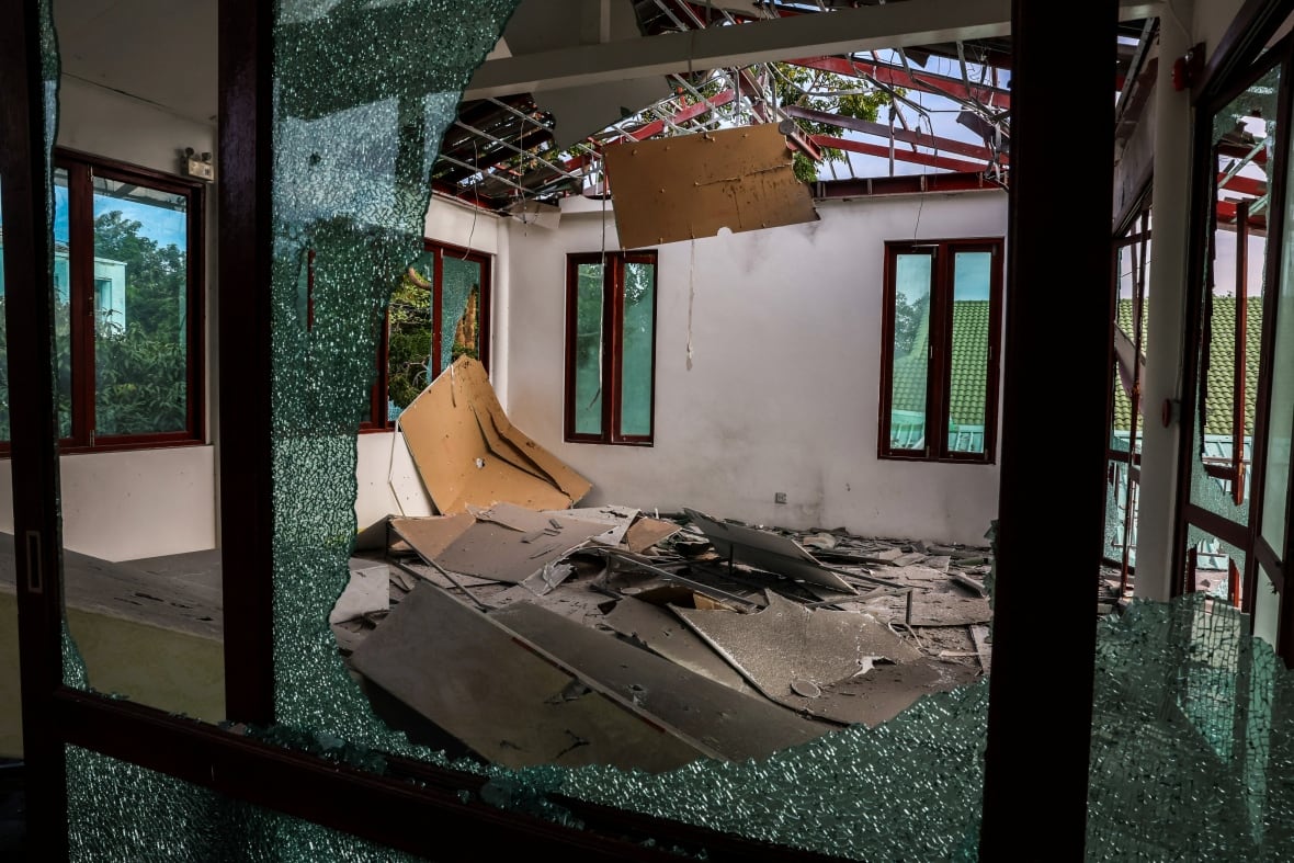 A damaged room is displayed with obsessed windows, with debris on the floor.