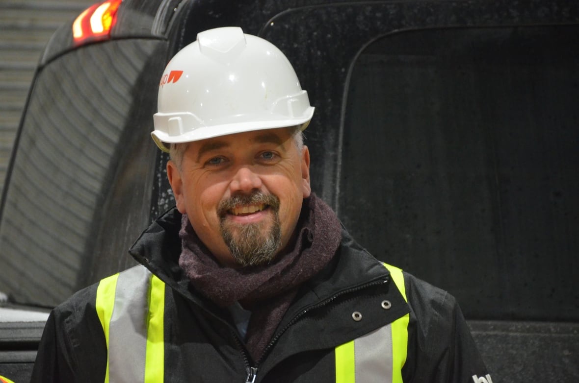 A man wearing a hard hat smiles for the camera 