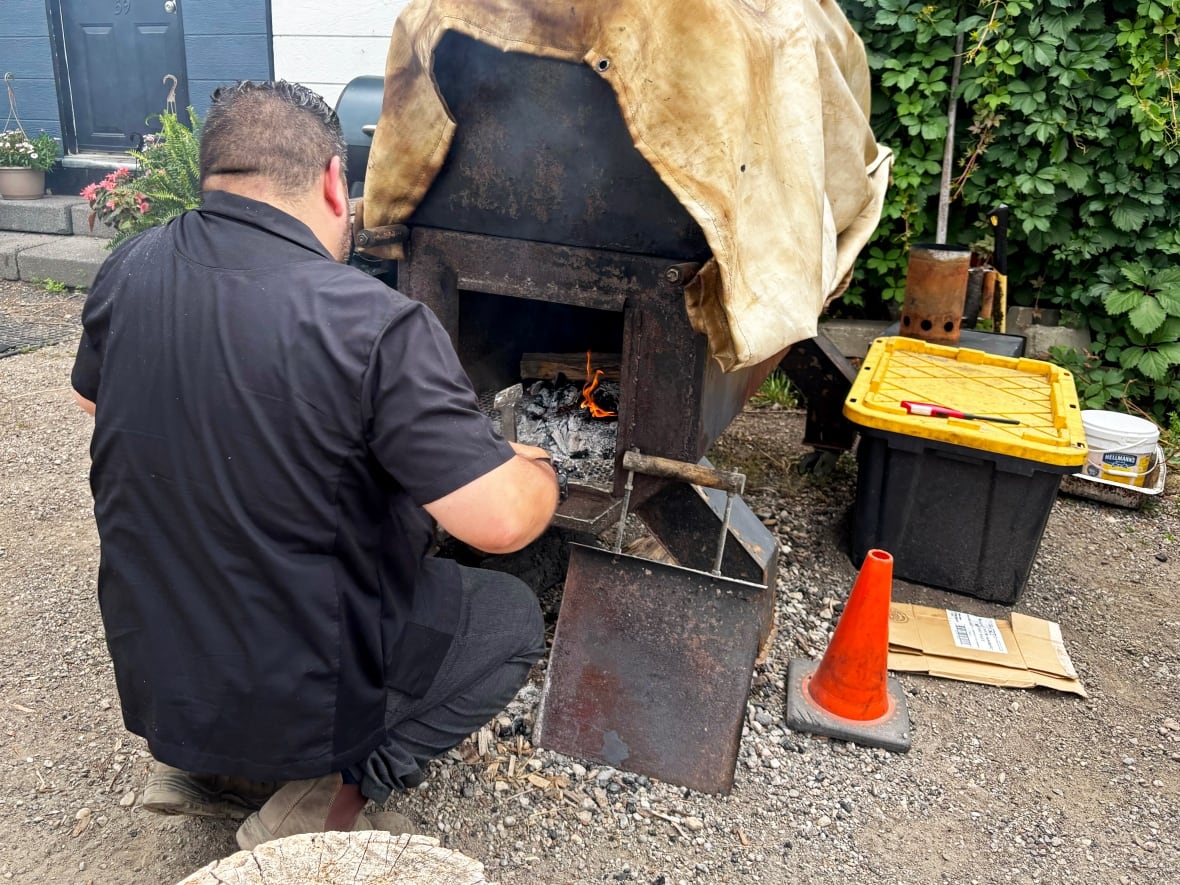 A man adds wood to a smoker