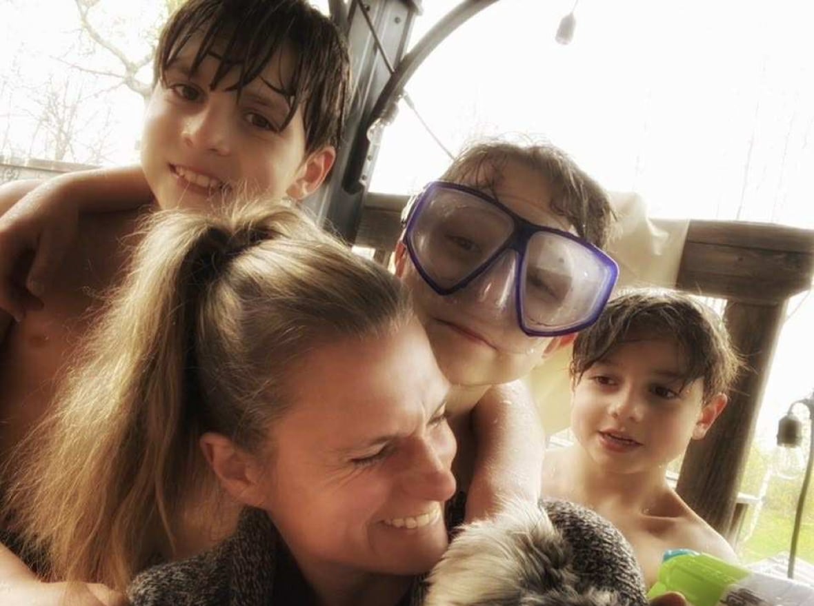 A woman is hugged by three children