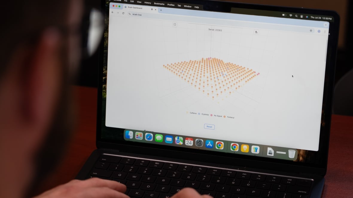 Man types on a laptop. Cube-like image appears on the screen.
