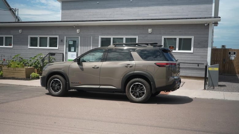 A grey SUV in front of a blue building