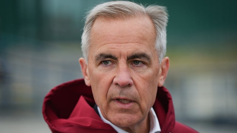 A man stands outside wearing a red jacket.