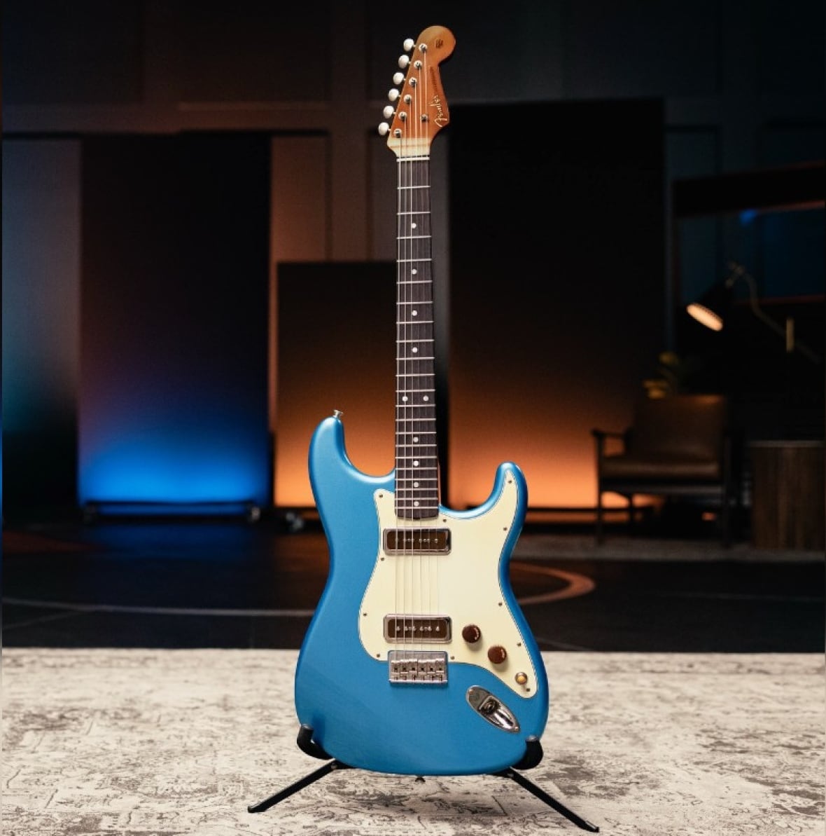 A blue electric guitar on a stand in front of a fireplace