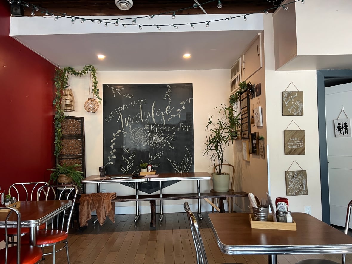 A blackboard on a wall is surrounded by tables and chairs.