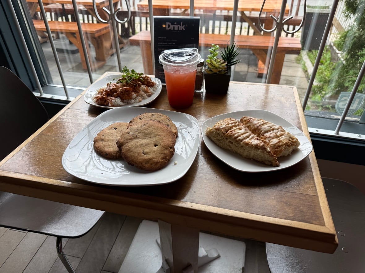 Plates of cookies and pastries sit on a table by a window.