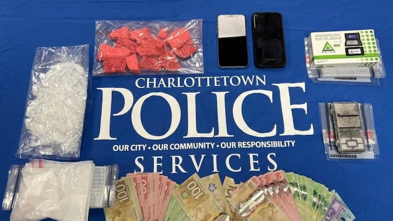 Money, drugs in baggies and cell phones are laid out on a table.