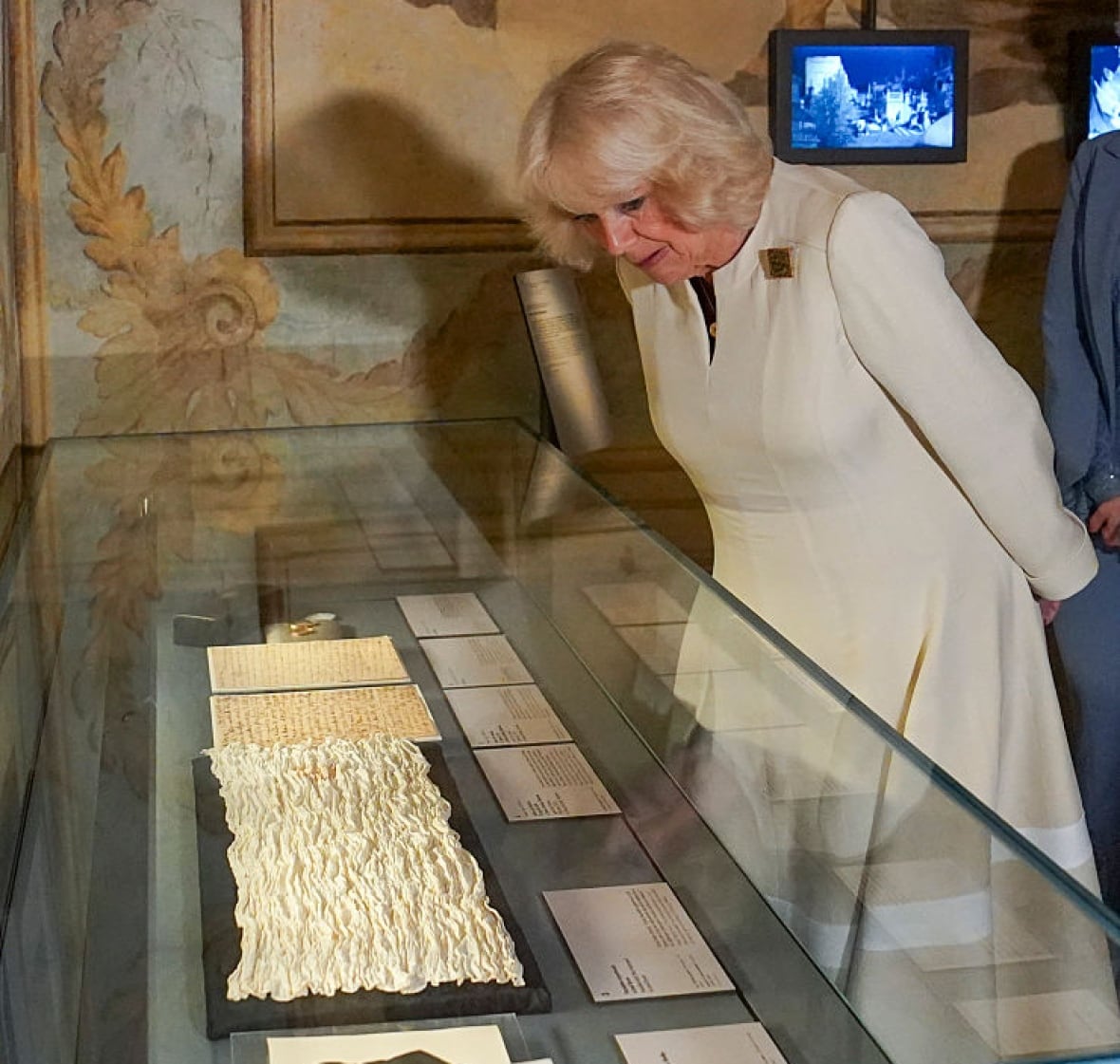 A person leans over a case in which there are several old books.