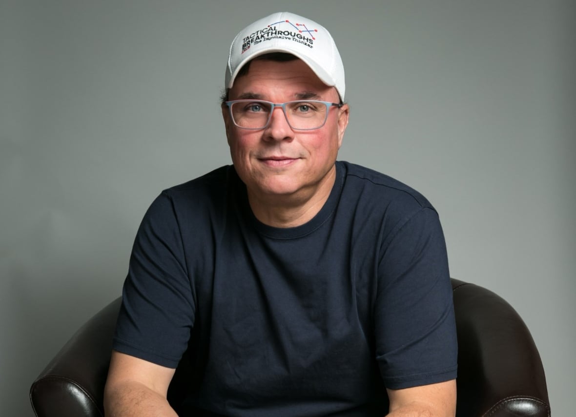 A man with a baseball hat and his hands together.