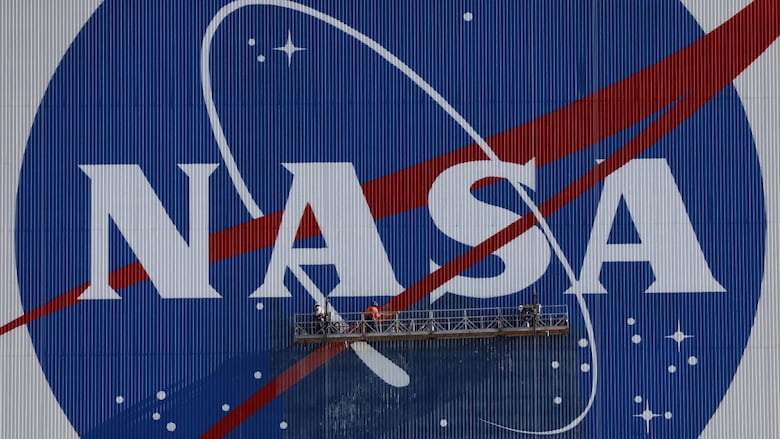 People stand on a lifted rig and paint a massive NASA logo