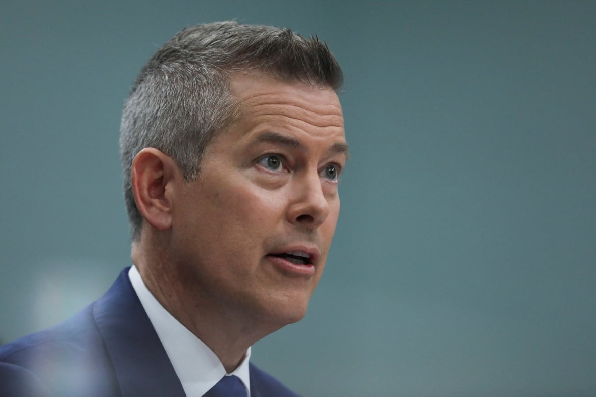 A man in a suit with gray hair looks to one side