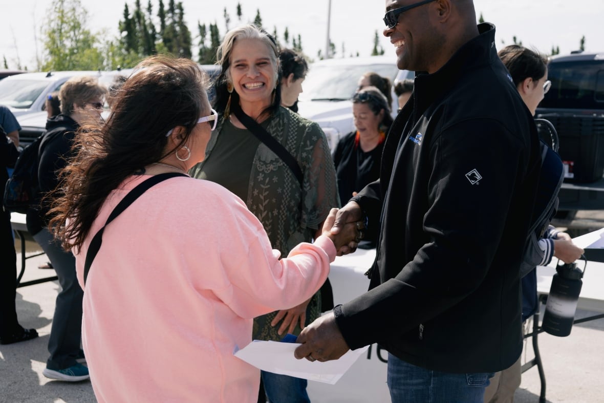 Three people shake hands.