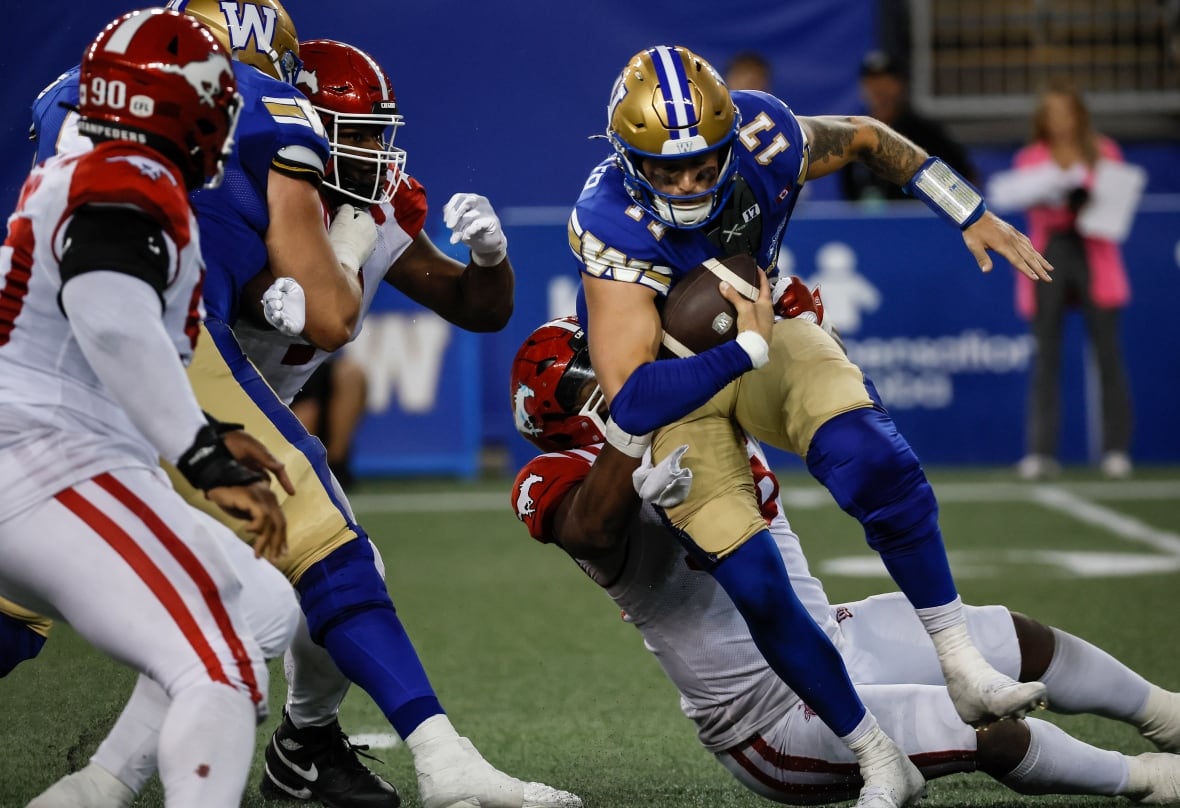 A player in white and red pulls down an opposing player in blue and gold.