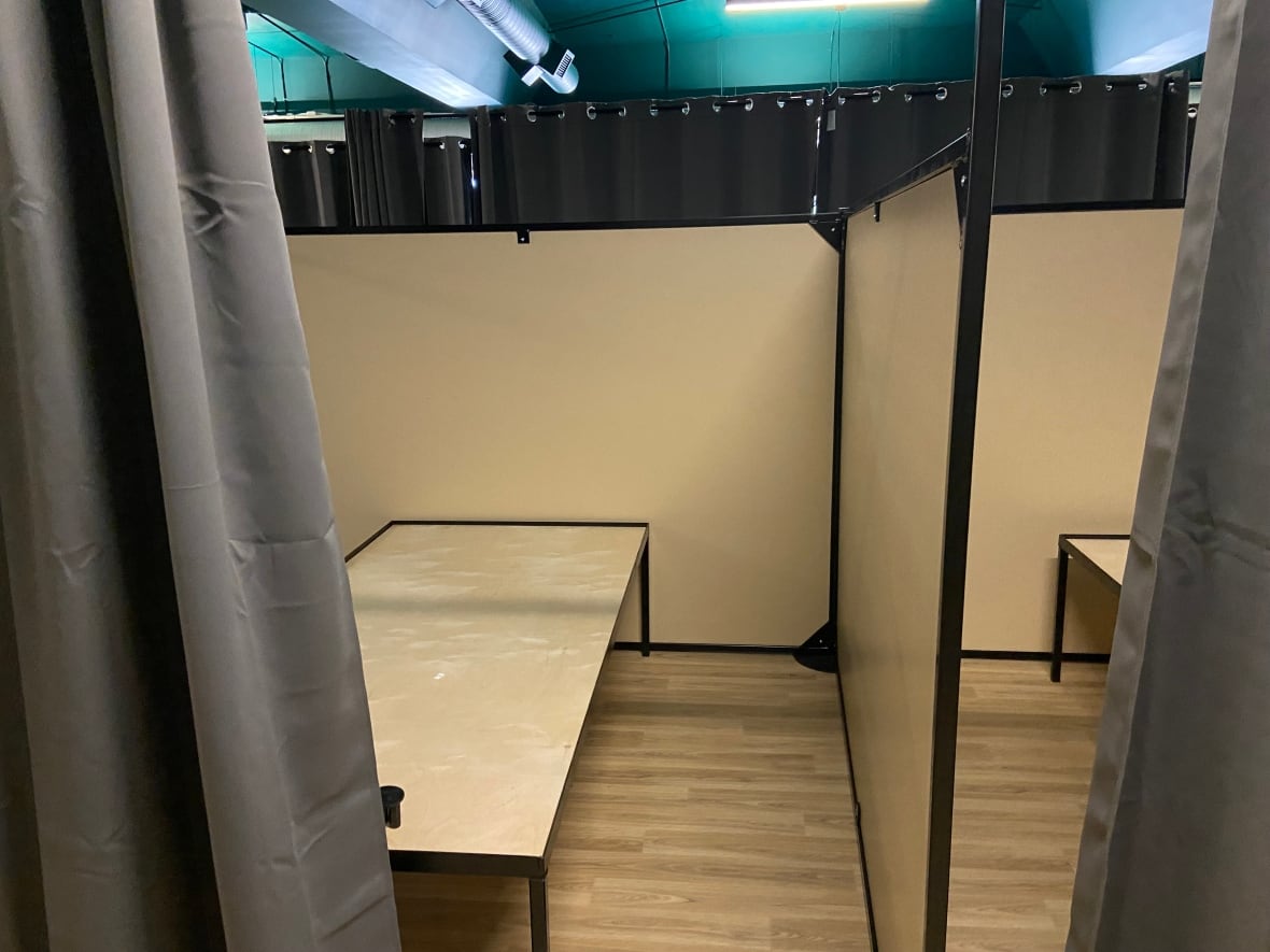 Beds separated by curtains and low barriers at homeless shelter.