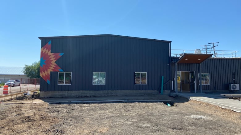 Exterior shot of navy blue building, with some construction equipment surrounding it. 