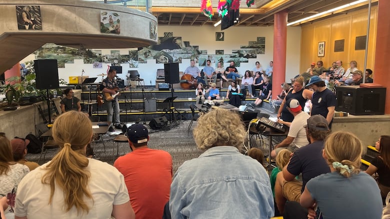 People in a sitting area of a university watching a musical performance.