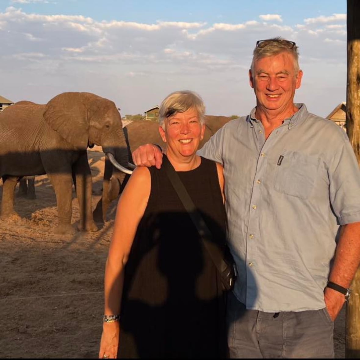 A couple smiles in front of an elephant.