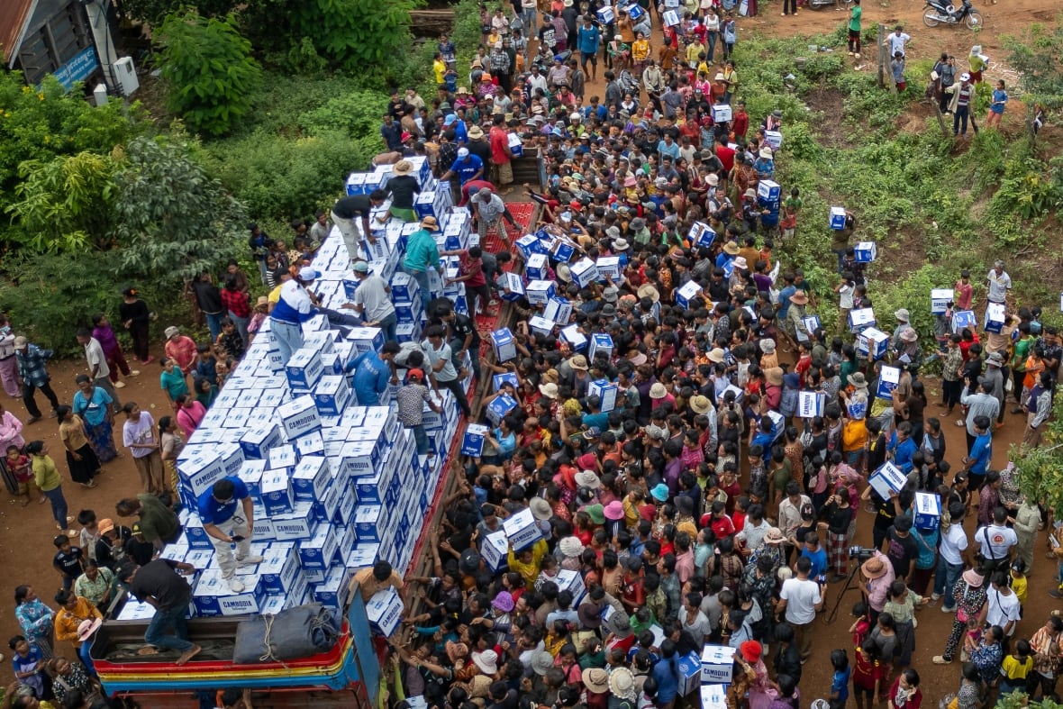 An aerial view shows people gathered around a truck as workers distribute aid.