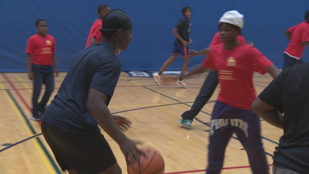 Teens play basketball in a school gym