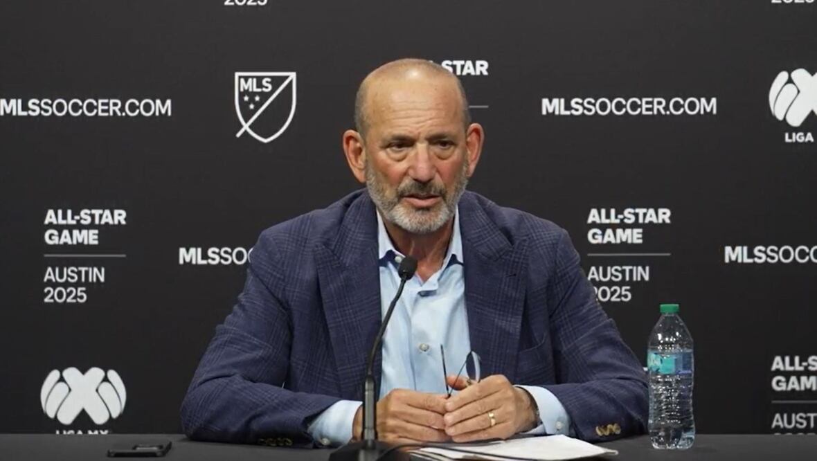 A bald, bearded man dressed in formals addresses the media during a press conference.