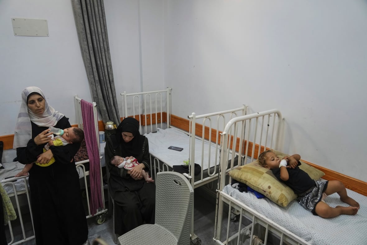 Two women care for their malnourished babies in hospital. A toddler is lying on a hospital bed.