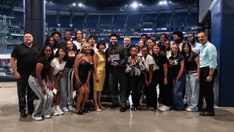 A group of people are posing for a photo with a man in the middle holding a certificate. 