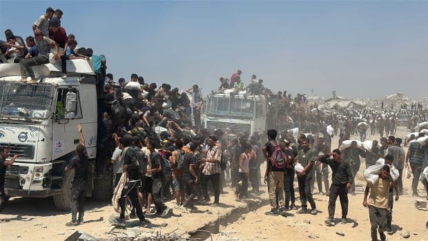 Hundreds of men rush a convoy truck to try and secure bags of humanitarian aid.