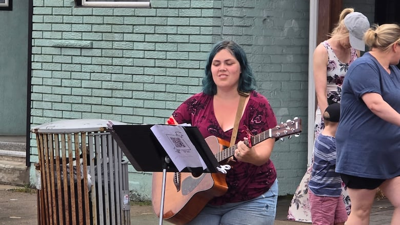 A woman sings and plays guitar.