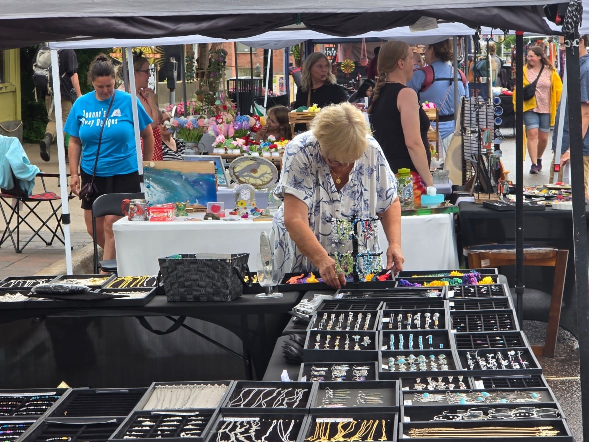 Vendors selling merchandise under tents at a street festival.
