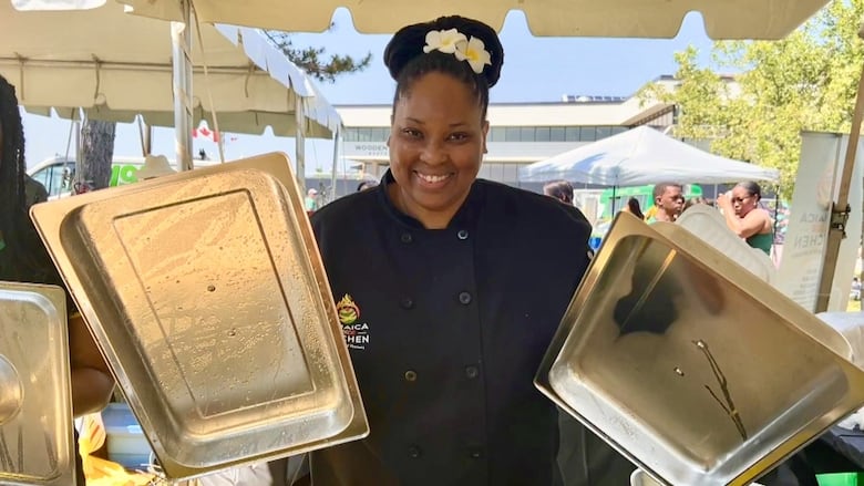 A woman smiles and lifts two silver tops.