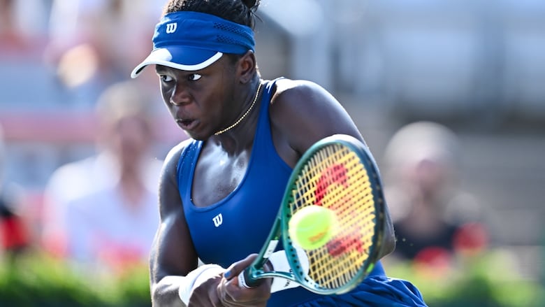 A women's tennis player hits a return shot.