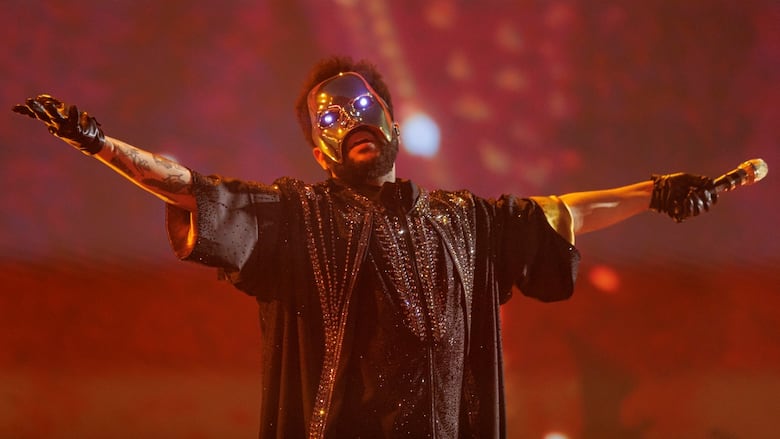 A man is shown wearing a mask and holding out a microphone.