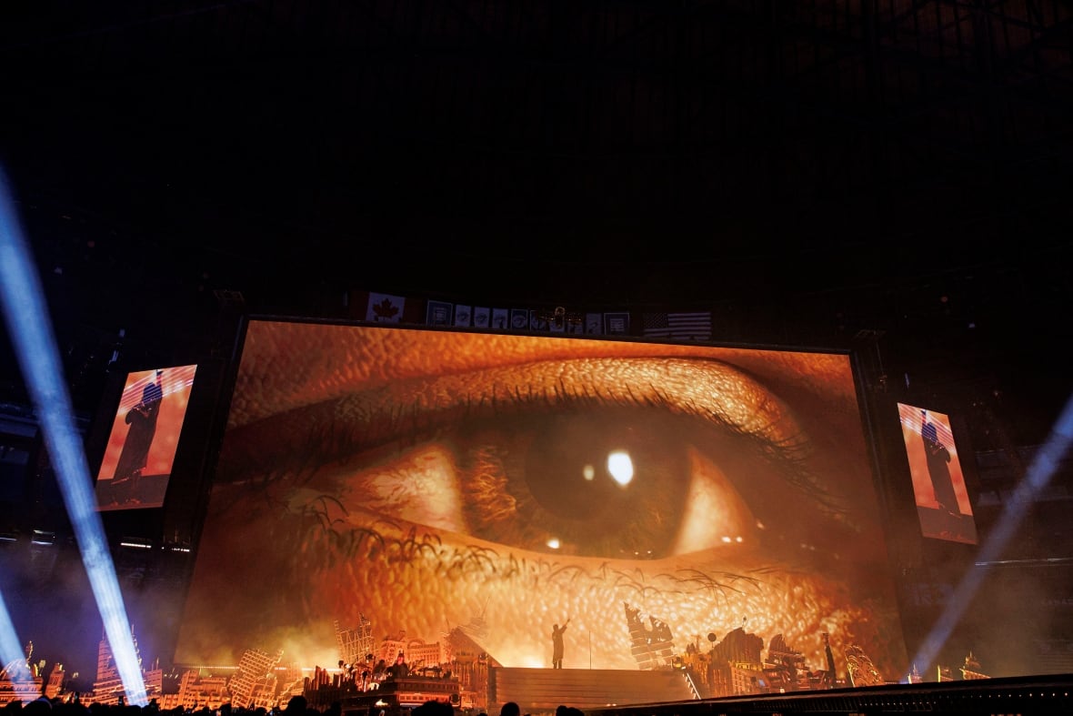 Se ve un ojo grande proyectado en una pantalla en un escenario.