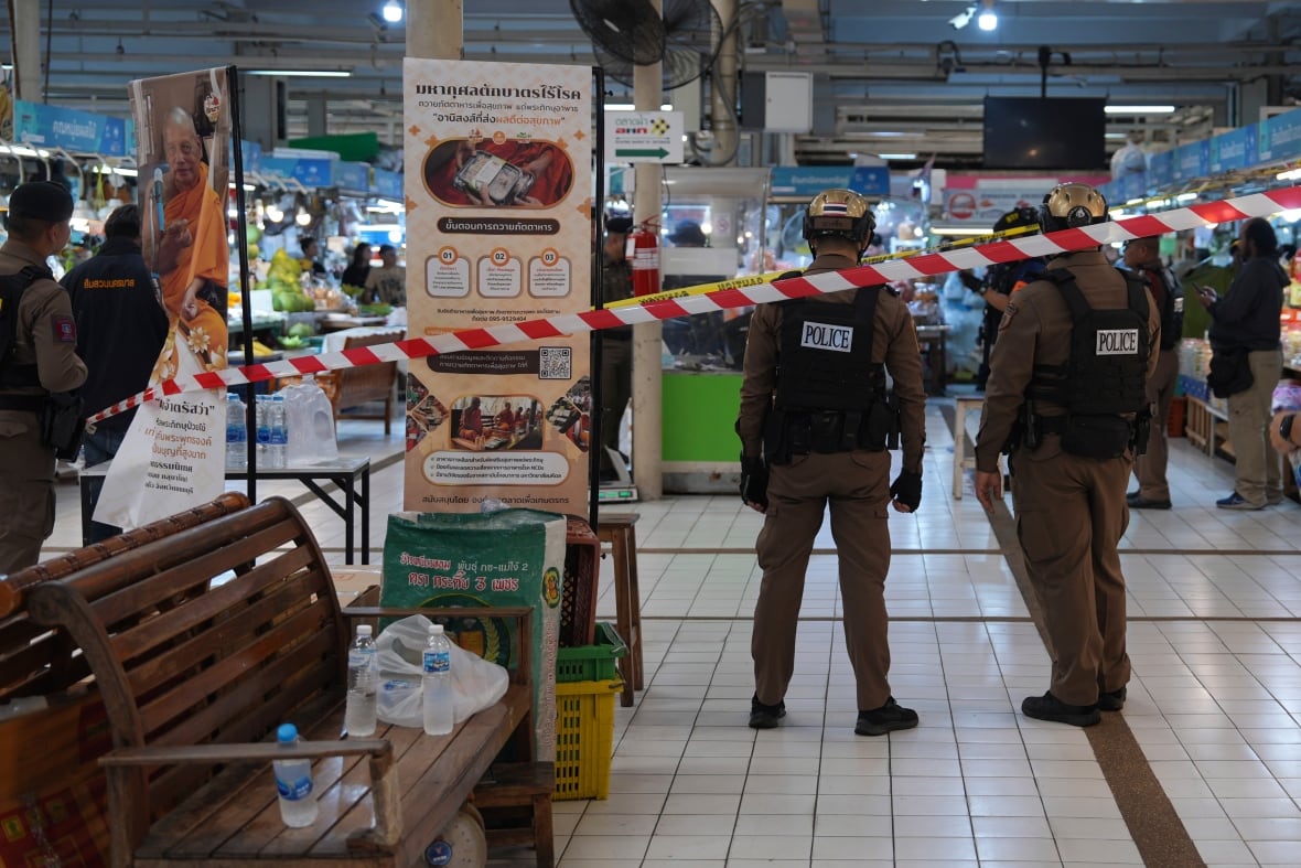 Police stand at a crime scene of a Bangkok market.