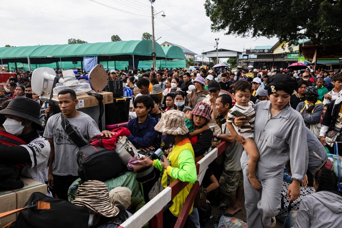 Displaced people wait at a border.