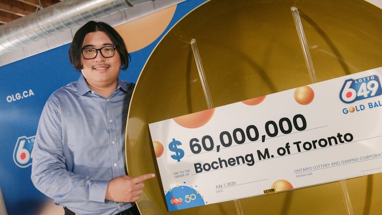 Photo of a man in glasses holding a giant cheque that reads $60,000,000. It is written to Bocheng M. of Toronto.