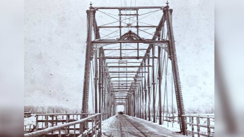 Black and white photo of an old steel truss bridge