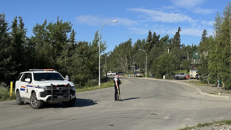 A police officer and a vehicle stopped in the street.
