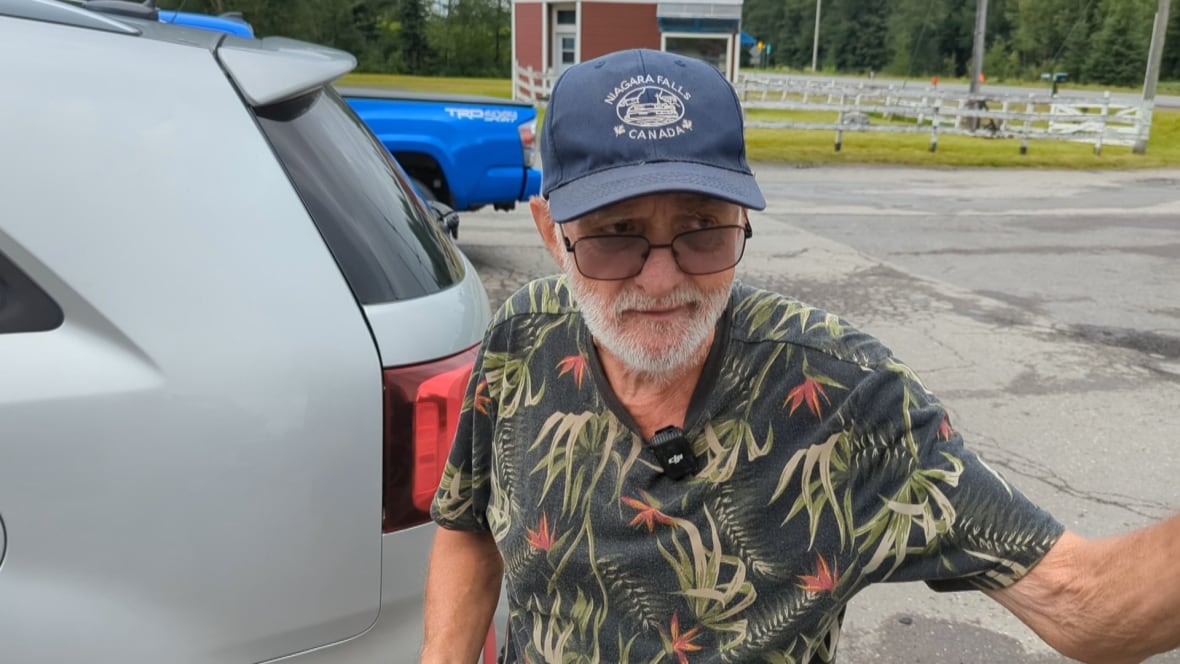 Man in hat gestures to his right.