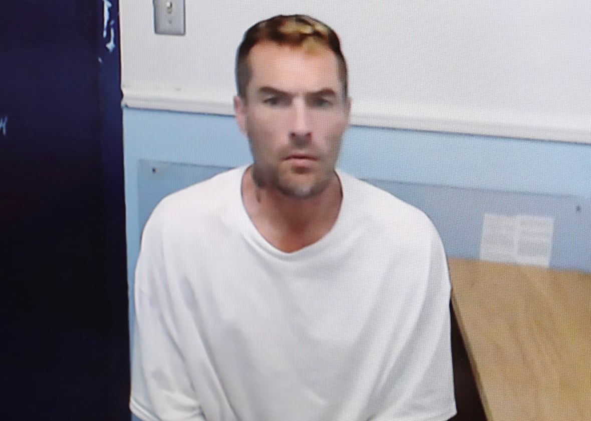 A man in a white shirt sitting next to a table.